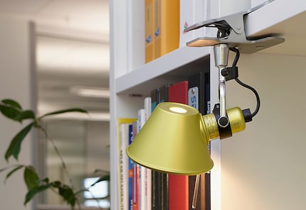 The Tolomeo Pinza Micro is clamped onto the shelf like a spider monkey, highlighting the bookcase.