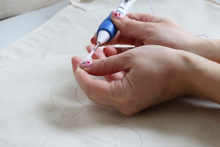 Use the fine wire to thread the yarn into the needle.
