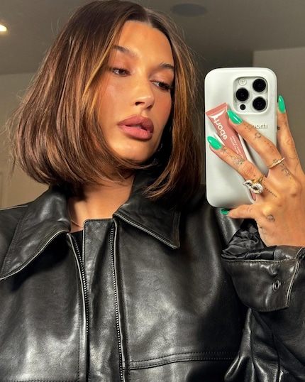 Hailey Bieber wears her Peptide Lip Tint on a specially designed mobile phone case. Now that's what I call useful merch.