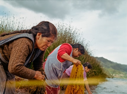 Zwei Frauen waschen frisch gefärbte Fasern im See. Chemische Farbstoffe würden giftige Substanzen in den abgeben, aber natürliche Farbstoffe fügen sich nahtlos in die Umwelt ein.